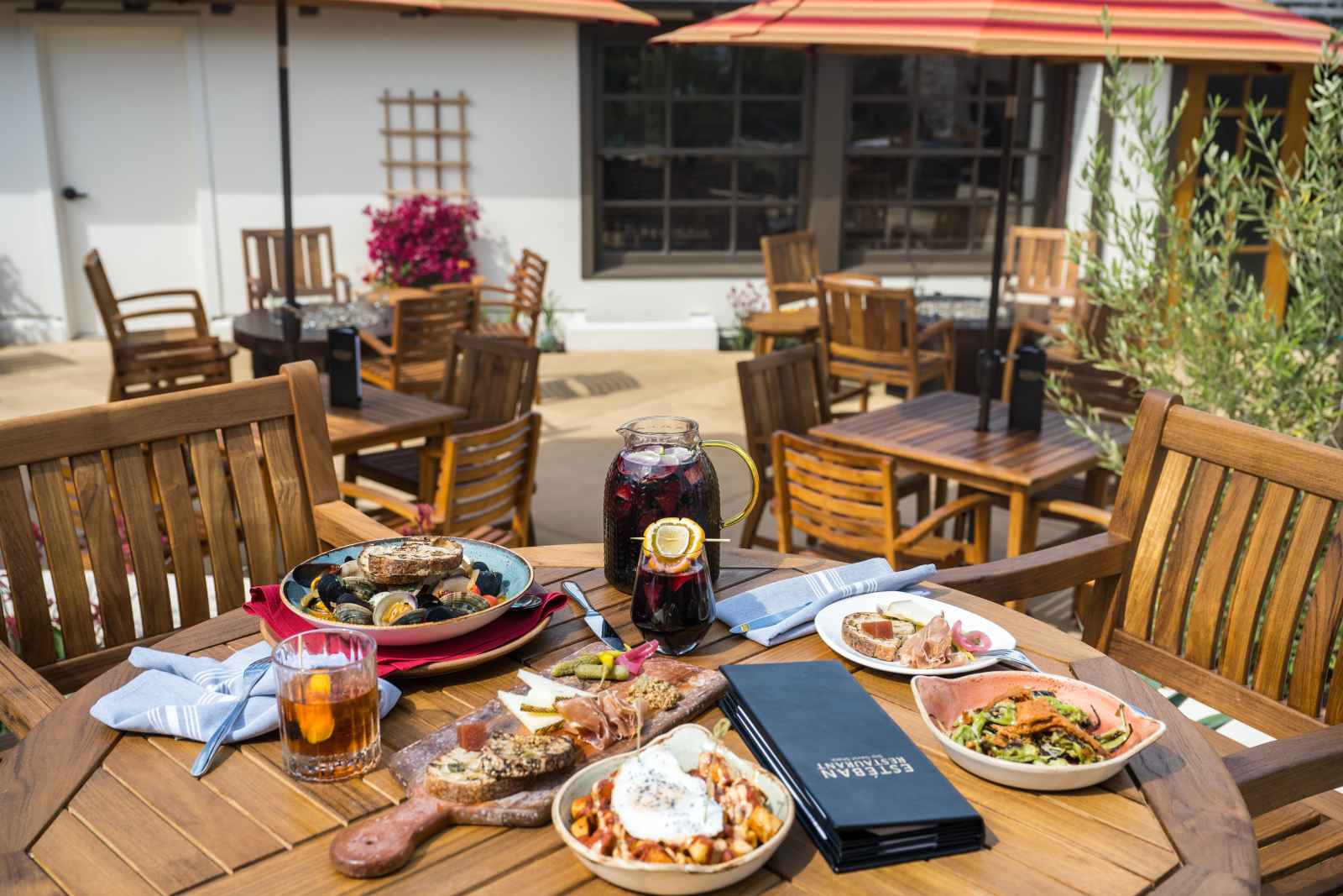 This is an image of an array  of dishes sitting on a wooden table on the outdoor patio of Esteban Restaurant in Monterey, California