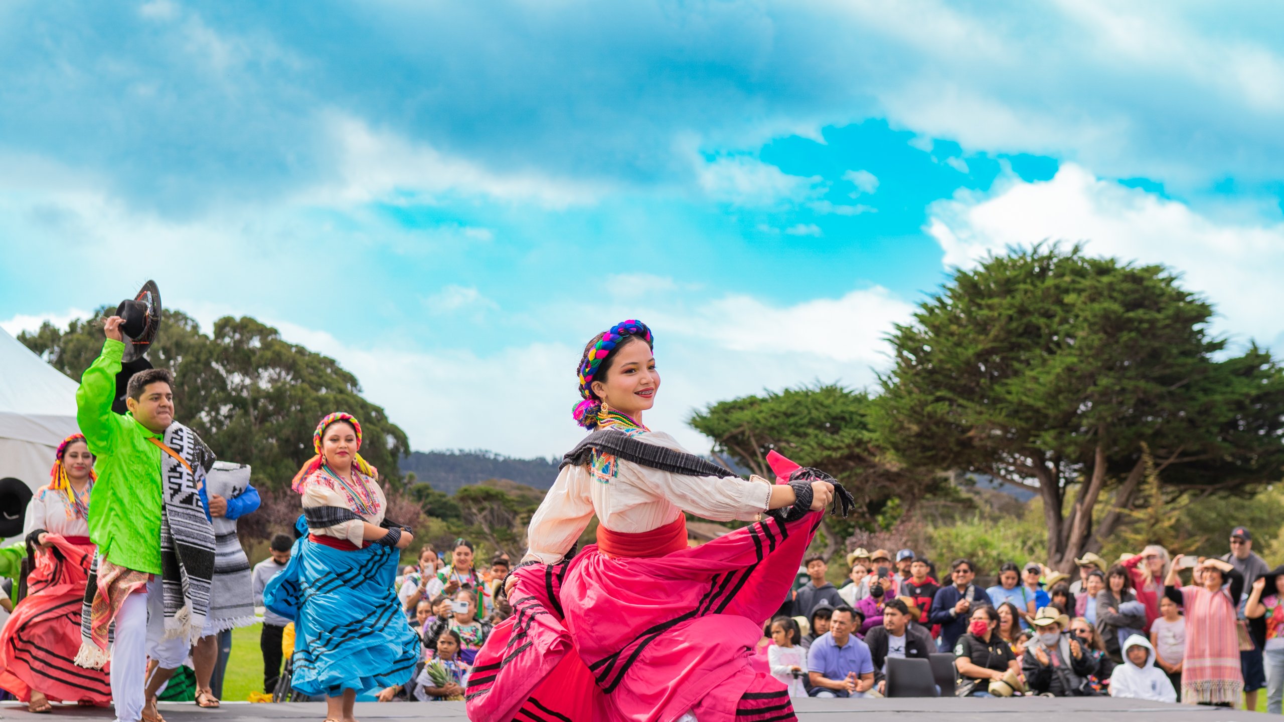 This is an image of a woman dancing on stage in traditional garments for the Oaxaca by the Sea event in Seaside, CA