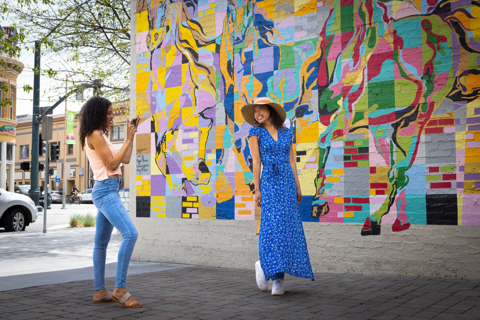 This is an image of a woman posing in front of a colorful mural in Salinas, California while her friend takes a photo