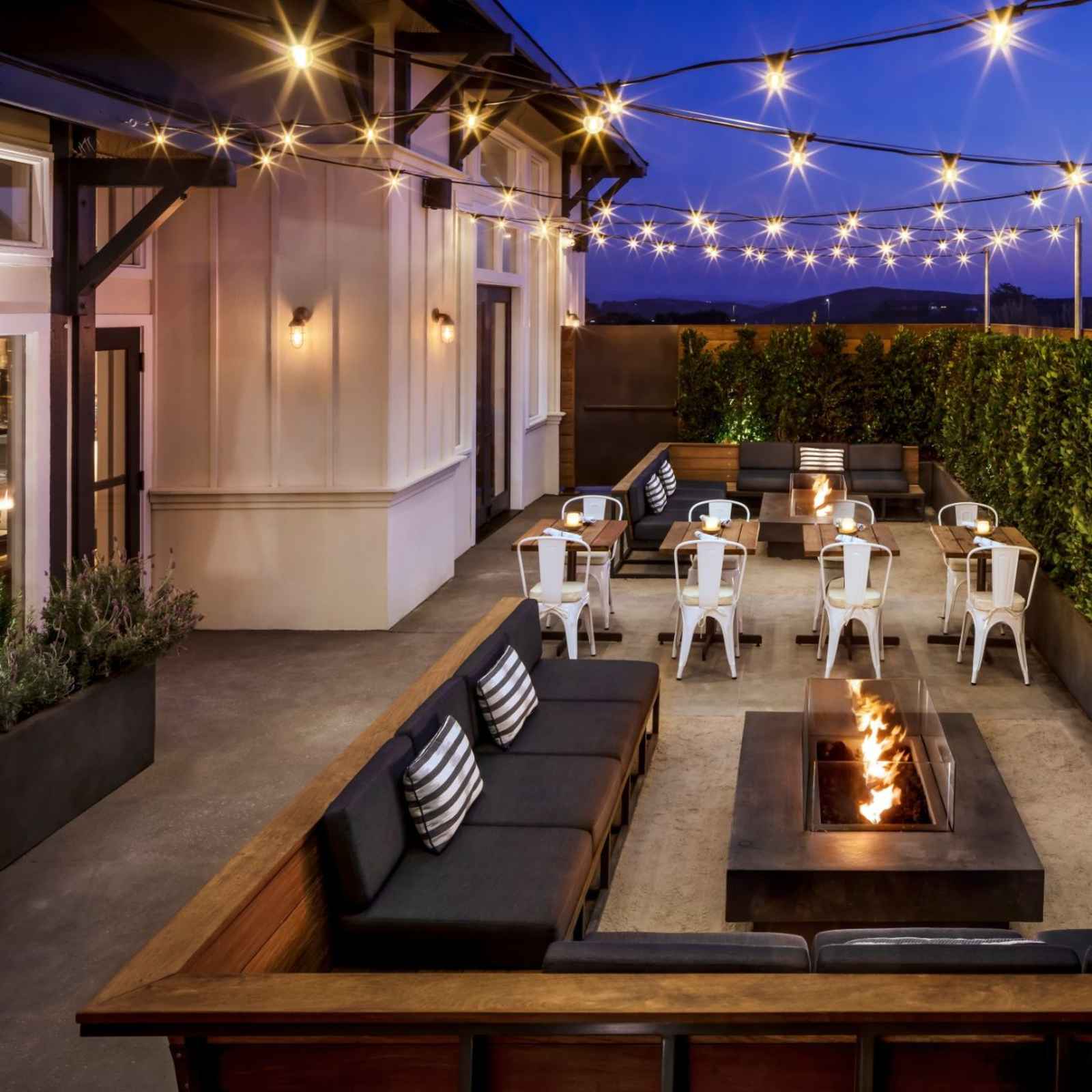 Table and chairs next to outdoor couches and a fire pit