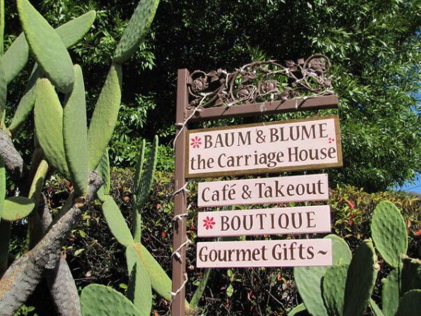 This is an image of the rustic, wooden signs for Baum & Blume and The Carriage House cafe and takeout restaurant