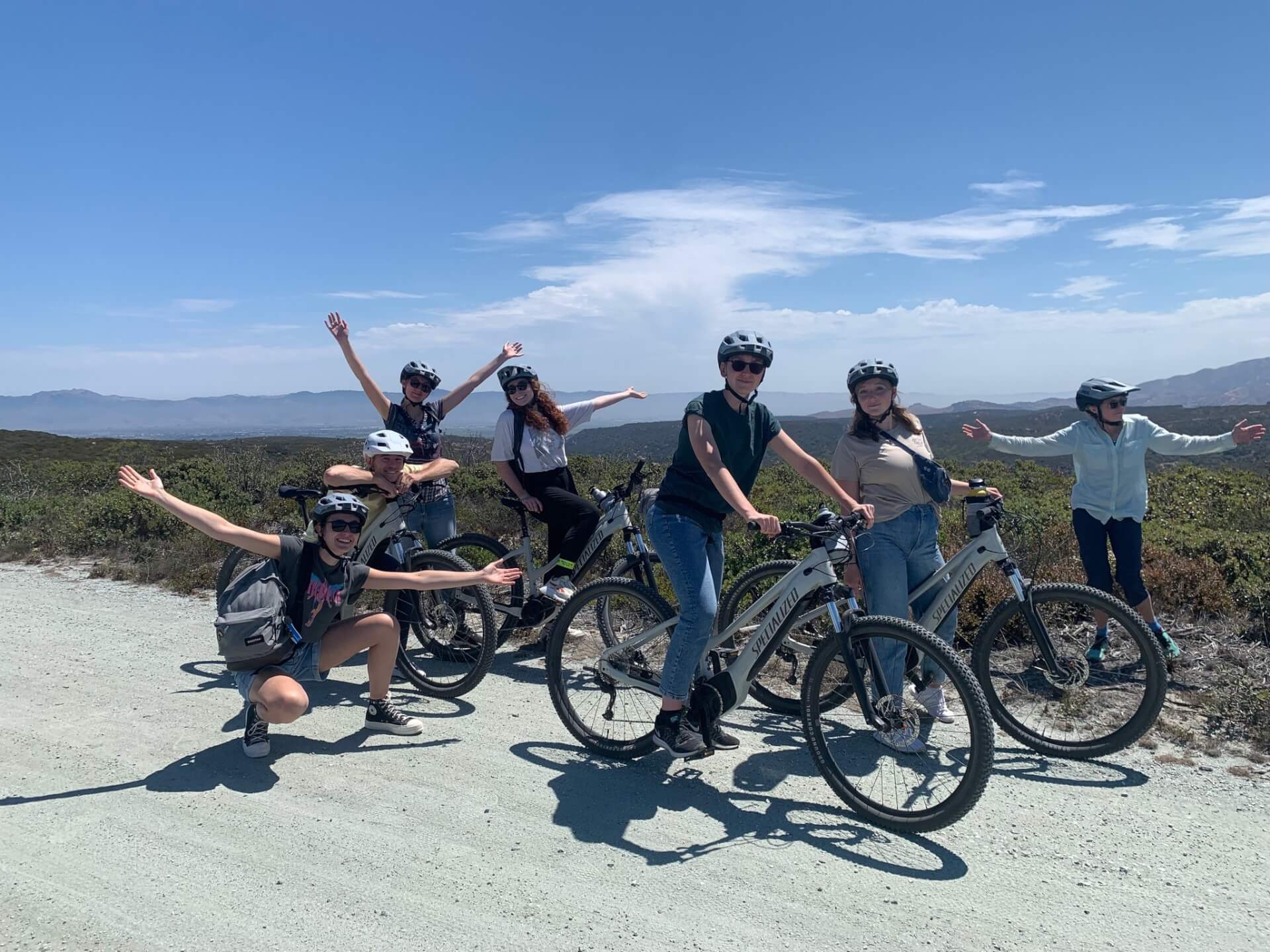 This is an image of a group of people smiling and posing for the camera on their bikes and helmets at Fort Ord National Monument on a VineCycle Tour